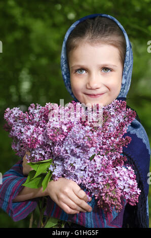 Petite fille avec des lilas fleurissent dans les mains Banque D'Images