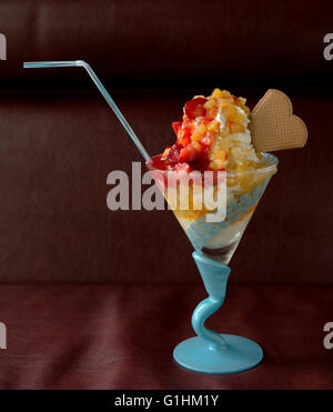 Beau grand verre avec des fruits et de la crème glacée et des biscuits en forme de coeur Banque D'Images