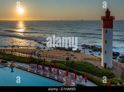 Des chaises longues et des parasols rouges en attente d'invités de la piscine d'un hôtel de luxe à Durban, KwaZulu Natal, Afrique du Sud Banque D'Images