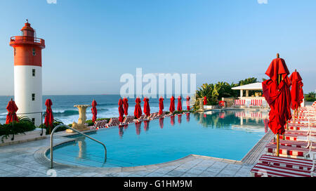 Des chaises longues et des parasols rouges en attente d'invités de la piscine d'un hôtel de luxe à Durban, KwaZulu Natal, Afrique du Sud Banque D'Images