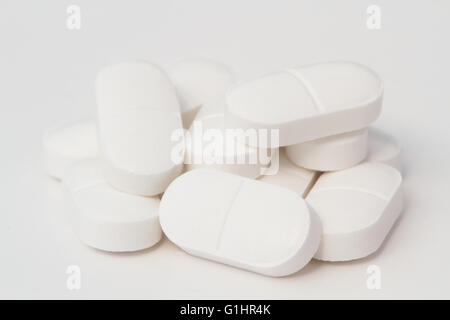 Un petit tas de comprimés de paracétamol ou analgésique blanc avec deux moitiés d'un cas isolé sur fond blanc. Banque D'Images