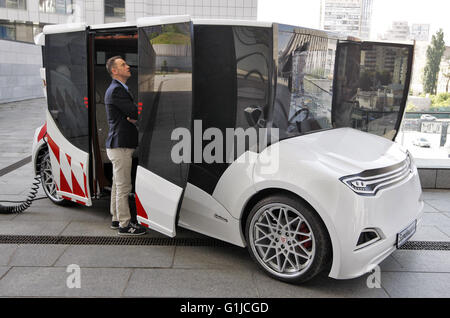 Kiev, Ukraine. 16 mai, 2016. Un homme d'oeil sur un prototype de voiture électrique premier Ukrainien 'Synchronous', au cours de présentation il à Kiev, Ukraine, le 16 mai, 2016. 'Synchronous" développé par entreprise ukrainienne Electric International Marathon est une voiture électrique avec moteur électrique innovant, panneaux solaires sur le toit, fenêtres panoramiques et l'extérieur qui me rappelle d'un chariot médiéval. La voiture en substance à l'utilisant comme une voiture de tourisme et de transport en taxi, et en mesure de surmonter la distance entre 130 et 160 kilomètres. © Vasyl Shevchenko/Pacific Press/Alamy Live News Banque D'Images