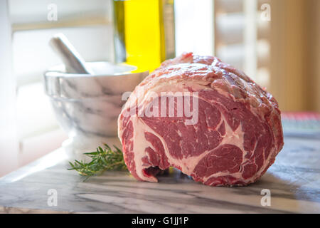 Côte de boeuf cru sur un sol en haut avec un sol de mortier et pilon et romarin . Banque D'Images