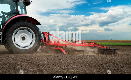 L'agriculture tracteur rouge champ cultiver plus de ciel bleu Banque D'Images