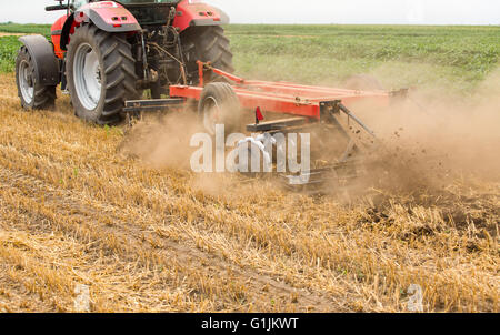 Le tracteur de cultiver les chaumes de blé champ, les résidus de récolte. Banque D'Images