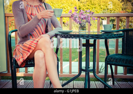 Une jeune femme est assise et boire le thé sur la véranda en été Banque D'Images