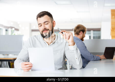 Happy young businessman sitting on barbus et en milieu de travail avec des documents Banque D'Images