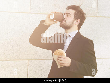 Businessman eating and drinking sur d'aller Banque D'Images