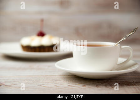 Gâteau avec une cerise et blanc tasse sur la table Banque D'Images