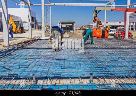 Les travailleurs de la construction l'installation de grillage métallique à l'emplacement de l'édifice. Banque D'Images