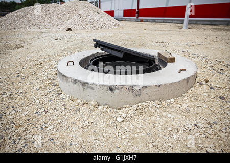 Close up de nouveau couvercle en métal sur le béton à trou de chantier de construction. Banque D'Images