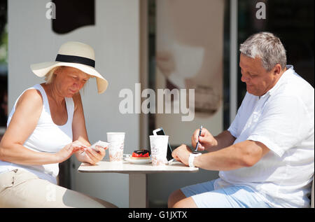 Couple sitting in cafe lors de l'utilisation de gadgets Banque D'Images