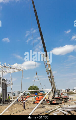 Grue mobile est transporter cadre métallique à l'assemblage. Les travailleurs sont d'aider sur le terrain. Banque D'Images