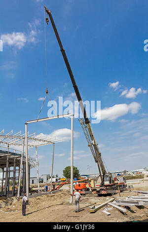 Grue mobile est transporter cadre métallique à l'assemblage. Les travailleurs sont d'aider sur le terrain. Banque D'Images