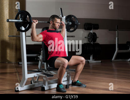 Puissance très sportif bodybuilder exécuter l'exercice avec haltères en sport sombre Banque D'Images