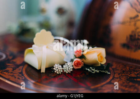 Close-up de mariée, accessoires. Jolie petite boutonnière avec boucles d'ellegant sur globe terrestre vintage Banque D'Images