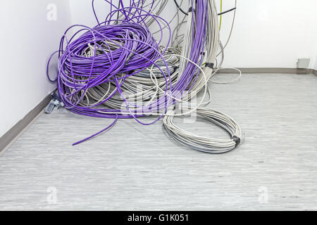 Un faisceau de câbles de communication sont suspendus au plafond dans la chambre. Banque D'Images