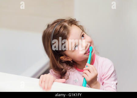 Petite fille en pyjama rose dans la salle de bain se brosser les dents Banque D'Images