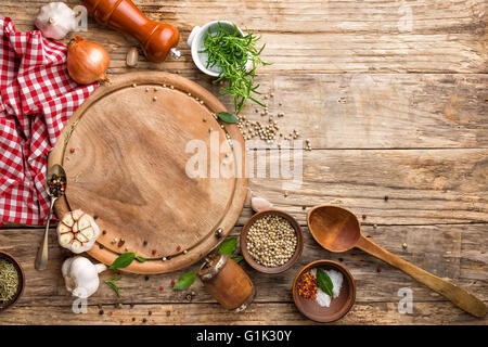 Contexte culinaire avec planche à découper vide et épices sur table en bois Banque D'Images