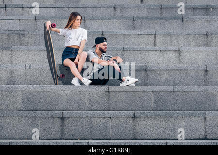 Couple dressed in style hippie sur escalier en béton dans la ville Banque D'Images