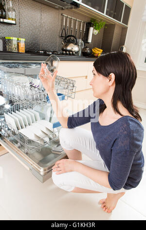 Femme à l'aide d'un lave-vaisselle dans une cuisine moderne. Appareil domestique. Banque D'Images