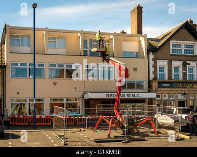 Les décorateurs à l'aide d'une plate-forme d'accès hydraulique pour peindre l'extérieur de la mens club de Redcar Banque D'Images