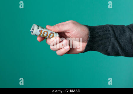 Human hand holding rolled up Monnaie dollar papier Banque D'Images