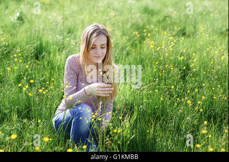 Jeune femme cueillette des fleurs sur une prairie d'été Banque D'Images