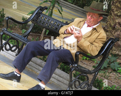 Homme plus âgé en utilisant son téléphone portable dans le parc Alameda Marbella, Andalousie Espagne Banque D'Images