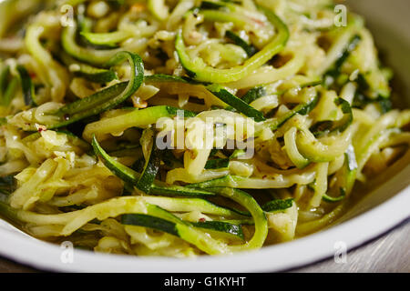 Des courges courgettes coupées en spirale avec de l'ail cuit dans l'huile d'olive Banque D'Images