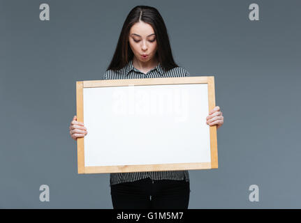 Young businesswoman showing blank board sur fond gris Banque D'Images