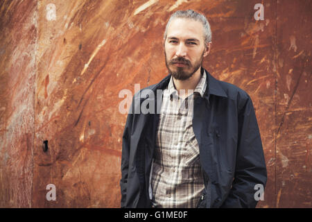 Portrait en extérieur d'homme asiatique barbu dans les tenues sur urbain rouillé grungy metal wall background Banque D'Images