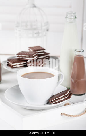 Tasse de café et quelques bouteilles de lait et chocolat lait frappé sur un plateau blanc sur fond blanc volets Banque D'Images