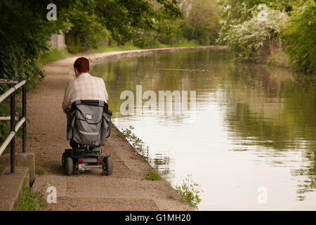 Un homme handicapé à l'aide d'un scooter pour personnes handicapées sur le chemin de halage, le Grand Union Canal à Warwick, Warwickshire, UK Banque D'Images