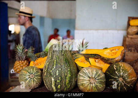 Homme portant chapeau panama vu dans l'arrière-plan derrière les étals de fruits du marché local dans la région de Santiago de Cuba, Cuba. Banque D'Images