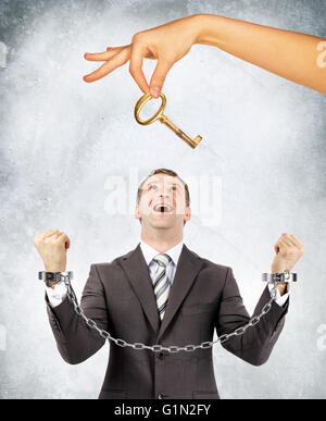 Businessman in handcuffs et grosse main offrant les principales Banque D'Images
