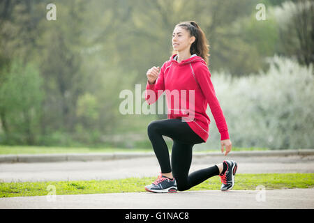 Portrait of sporty woman doing stretching exercises in park avant l'entraînement. La préparation de l'athlète féminine pour faire du jogging en plein air Banque D'Images