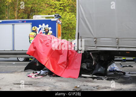 Une voiture est couverte d'une bâche entre deux camions après un accident sur l'autoroute A6 près de Nuremberg, Allemagne, 17 mai 2016. Dans l'accident survenu mardi au moins quatre personnes ont été tuées. Photo : Daniel Karmann/dpa Banque D'Images