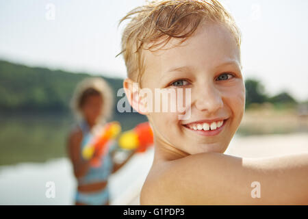 Happy boy au lac sur les vacances à jouer avec un pistolet squirt Banque D'Images