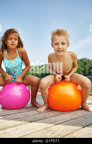 Deux enfants heureux assis sur un spacehooper dans un lac en été Banque D'Images