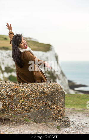 Jeune femme faisant l'expression originale tout en étant assis sur un rocher. Les falaises blanches de Douvres, Dover, Kent, UK Banque D'Images