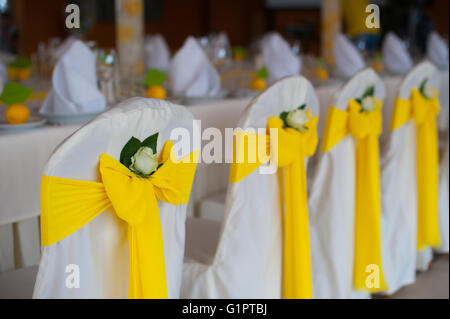 Chaises avec arcs jaune sur le dîner de mariage Banque D'Images