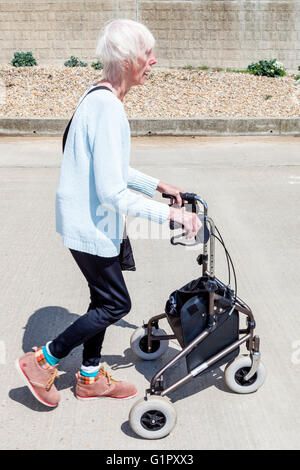 Une vieille femme handicapée à l'aide d'un3903 aide à la marche, Brighton, Sussex, UK Banque D'Images