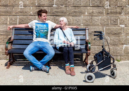 Une vieille femme handicapée assise sur un banc à parler à son petit-fils, Brighton, Sussex, UK Banque D'Images