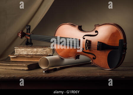 Ancien violon avec rouleaux de feuille de musique et de vieux livres sur une table en bois, still life Banque D'Images