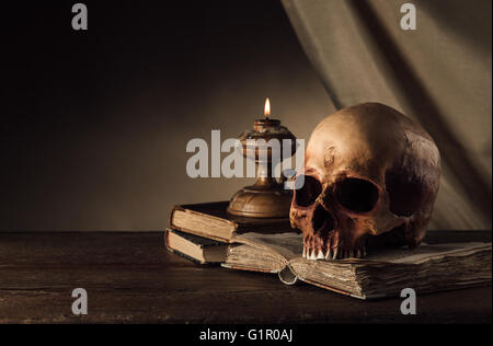 Crâne humain, bougie allumée et ouverte livre ancien sur une vieille table en bois, des connaissances et de l'alphabétisation concept Banque D'Images