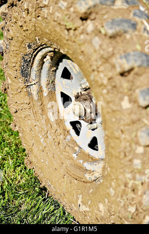 Gros véhicule off road pneu et roue pleine de boue sur l'herbe verte Banque D'Images