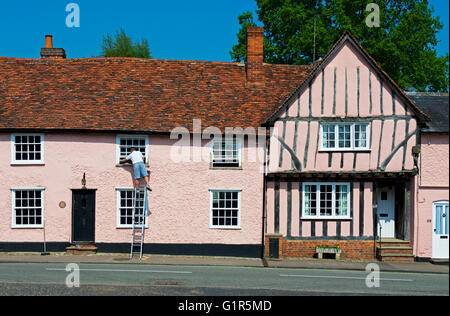 Homme debout sur l'échelle, à côté de maison à pans de bois de long Melford, Suffolk, Angleterre, Royaume-Uni Banque D'Images