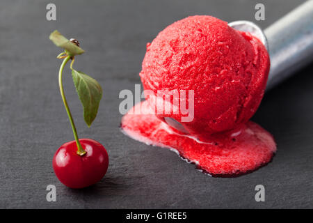 La crème glacée, de cerise, framboise, fraise, canneberge, rouge sorbet, scoop. Arrière-plan de la pierre noire Banque D'Images