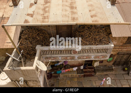 Eyriel vue d'un étain ancien typique maison de village avec toiture en bois de chauffage empilé en balcon et le séchage des vêtements sur string à l'entrée. Banque D'Images